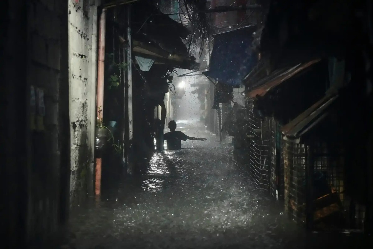 A man wades through waist-deep floods in a residential area of Quezon City.