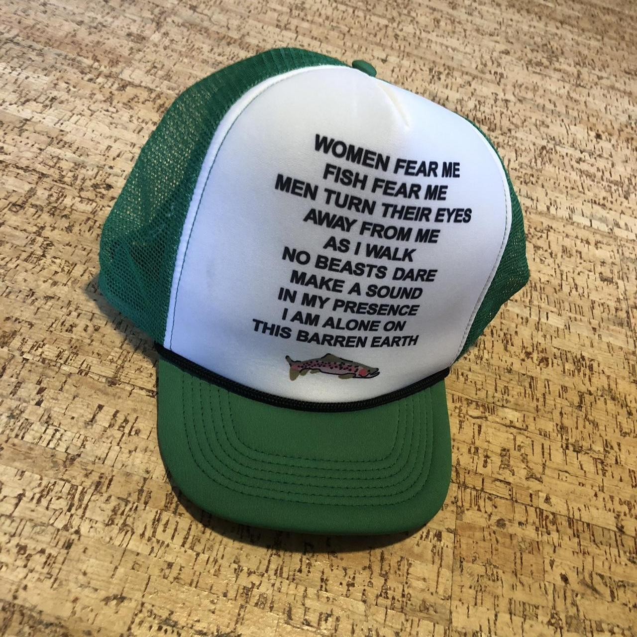 A trucker hat with the caption "Women fear me; fish fear me; men turn their eyes away from me as I walk; no beast dare make a sound in my presence; I am alone on this barren Earth; 🐟"