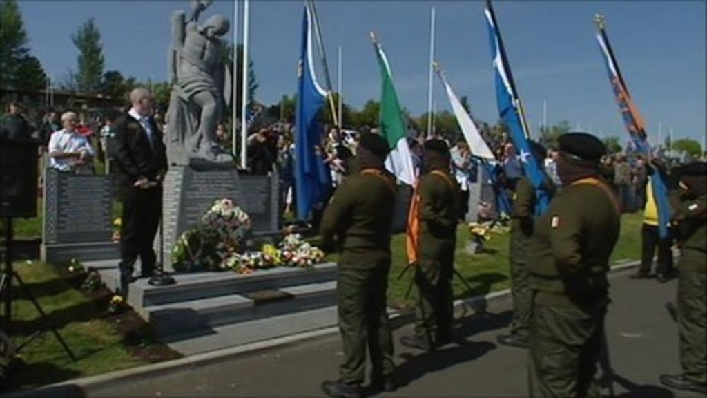 PIRA members in uniform and balaclavas standingin formation with flags in public